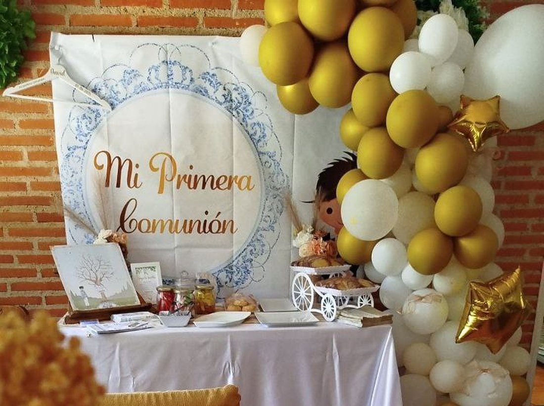 Mesa de comunión con su cartel, el arco de globos dorados y la mesa de detalles